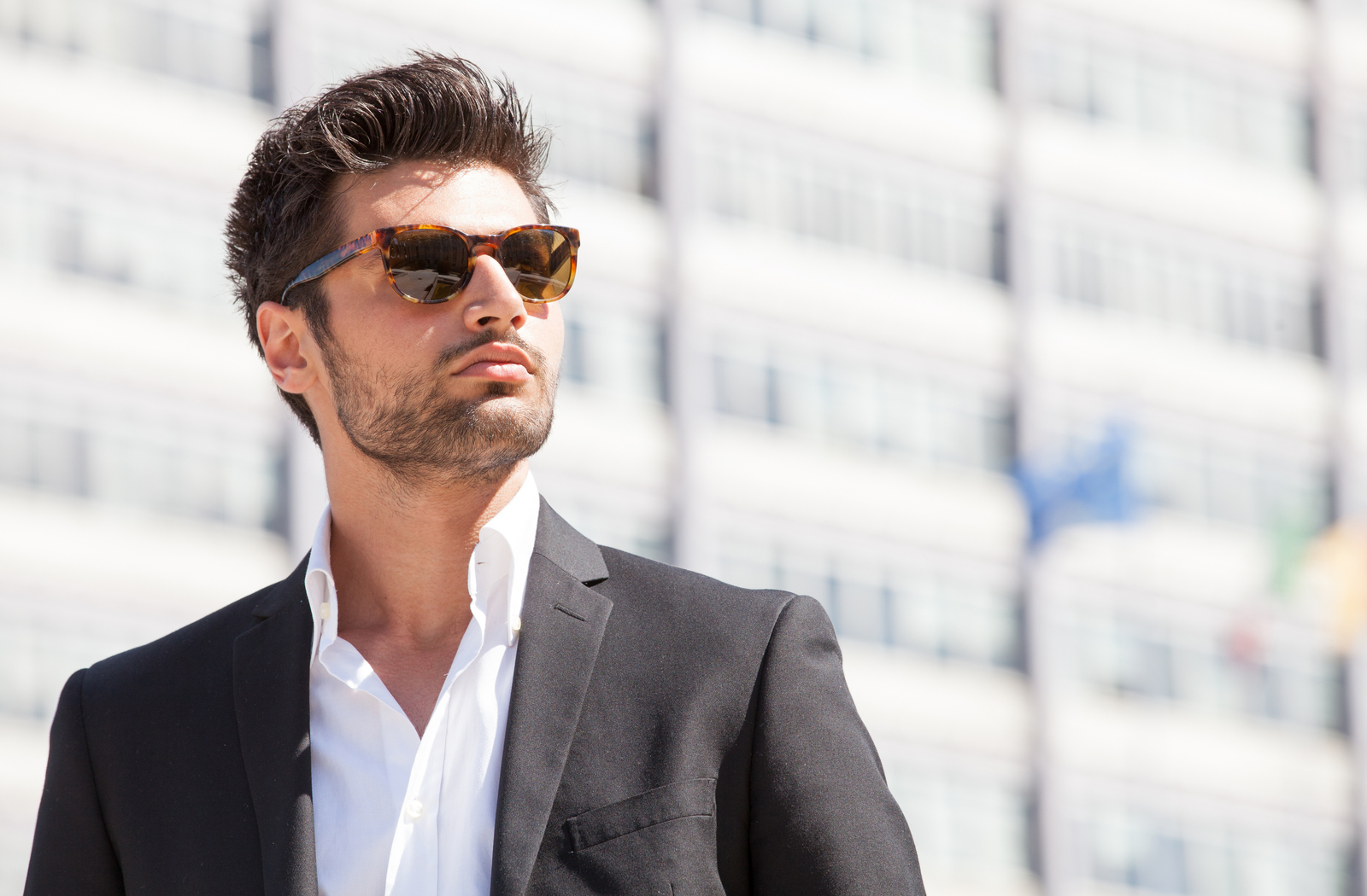 Young professional man in suit wearing sunglasses to protect eyes while outside in the sun