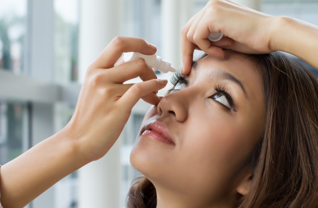 Women applying eye drops to eyes to prevent dry eye