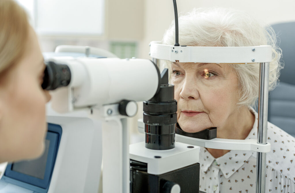 An optometrist performing a slit-lamp exam to an older adult woman to detect eye problems.