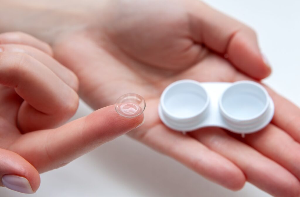 Pair of hands holding a contact lens and open contact lens case.